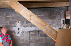 man in basement, inspecting walls, and staircase